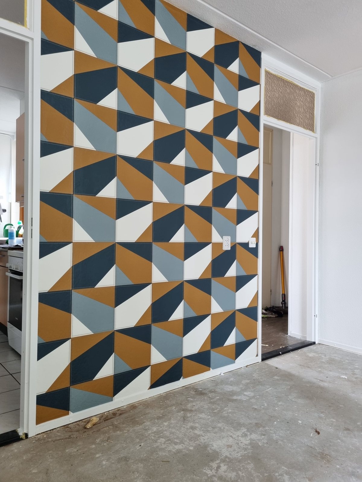 Wand met een grafisch driehoekbehang in oker, blauw en wit