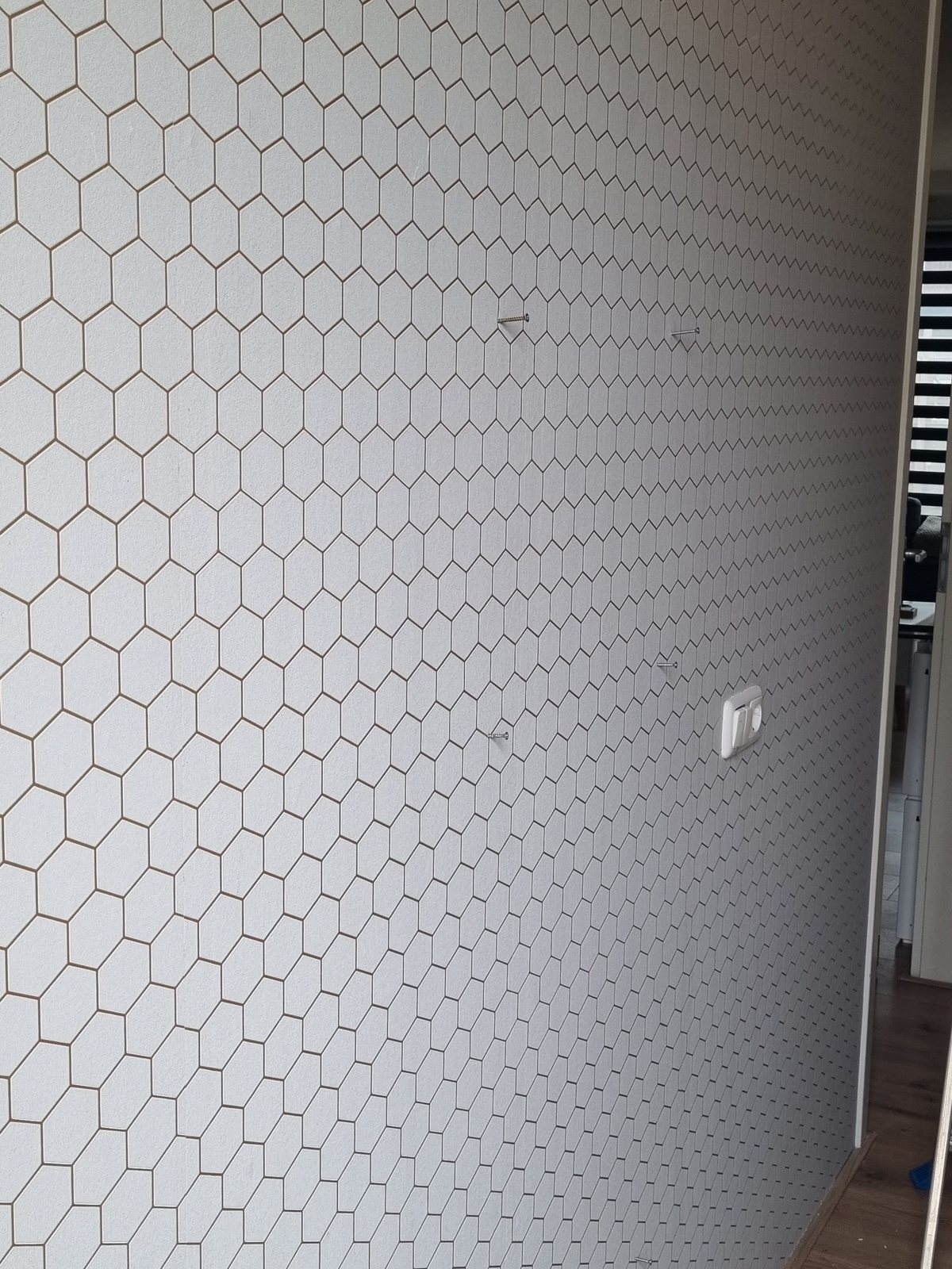 Wand met witte hexagon-tegels, gelegd door Micmaa&rsquo;s