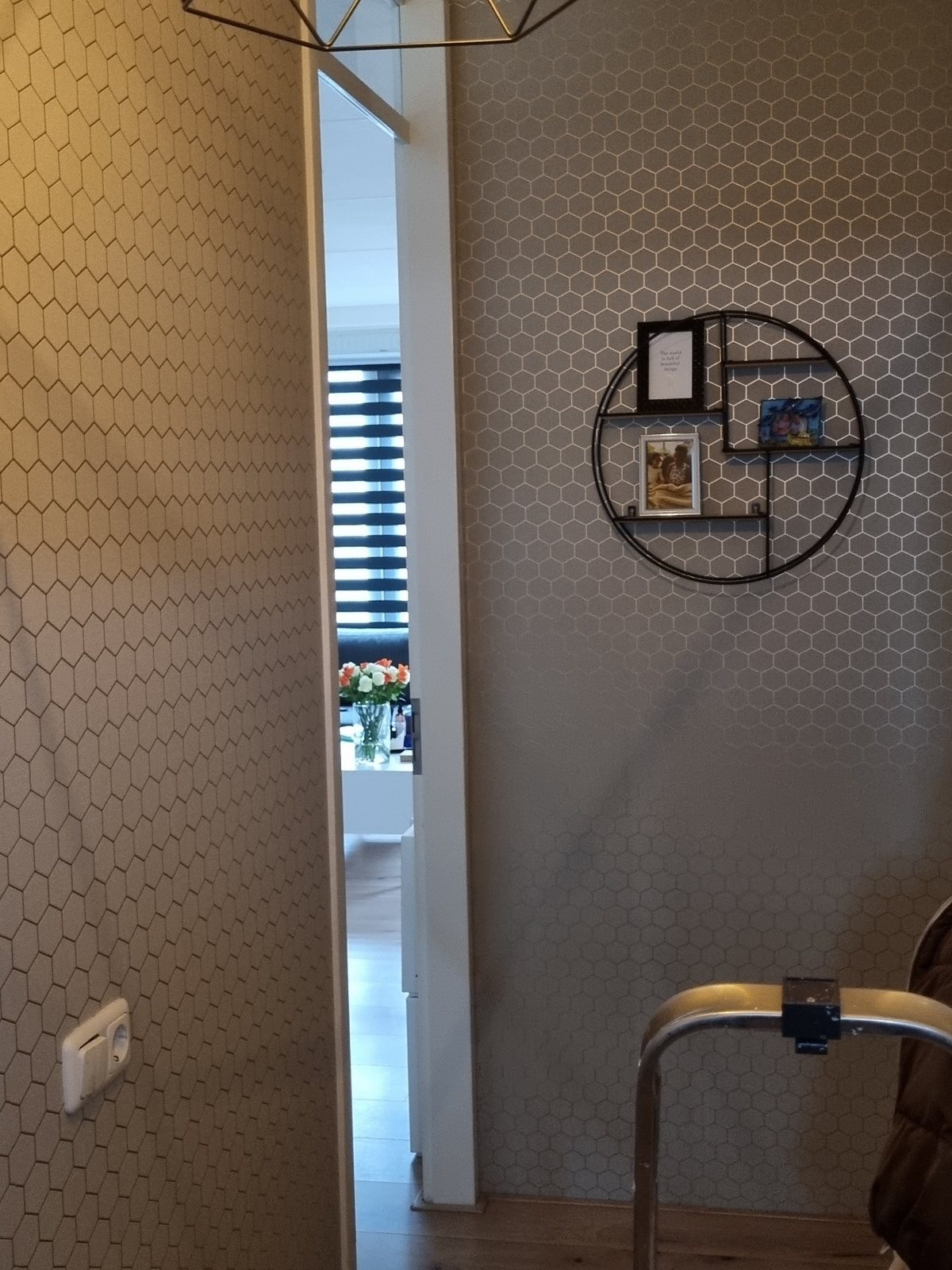 Gang met hexagonbehang, een wandrek en een nieuw kozijn