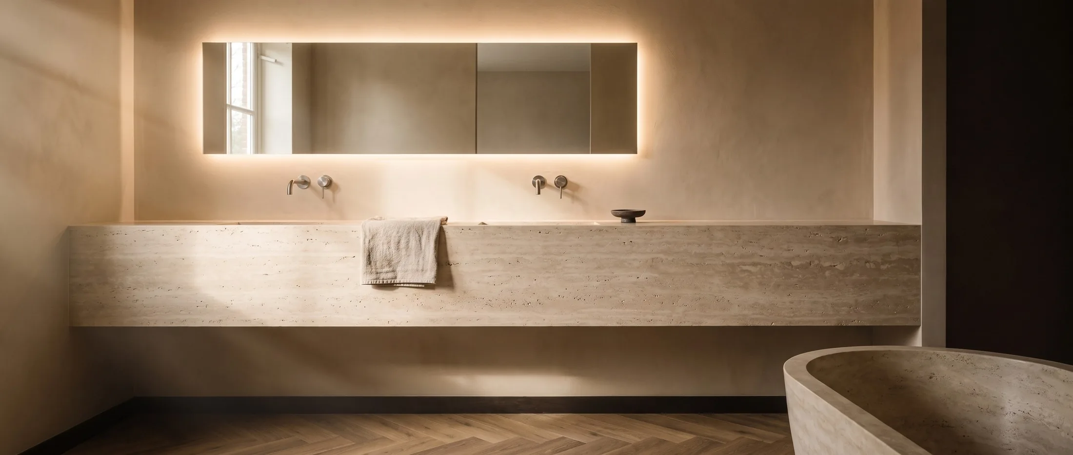 Serene badkamer met travertijn wastafelblad, verlichte spiegel en vrijstaand bad